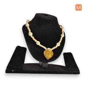 A Tulsi Kanthi mala featuring light-colored, round beads, some inscribed with 'Radhe', and a heart-shaped golden pendant depicting Radha and Krishna, displayed on a black jewelry stand against a clean white background
