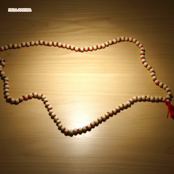 Lifestyle product photo of MalaMantra Red String Mala on a neutral-toned surface.