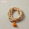 Close-up of smooth, white hand-knotted Tulsi mala beads for meditation, showing orange knotting between each bead.