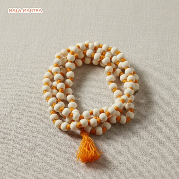 Close-up of smooth, white hand-knotted Tulsi mala beads for meditation, showing orange knotting between each bead.