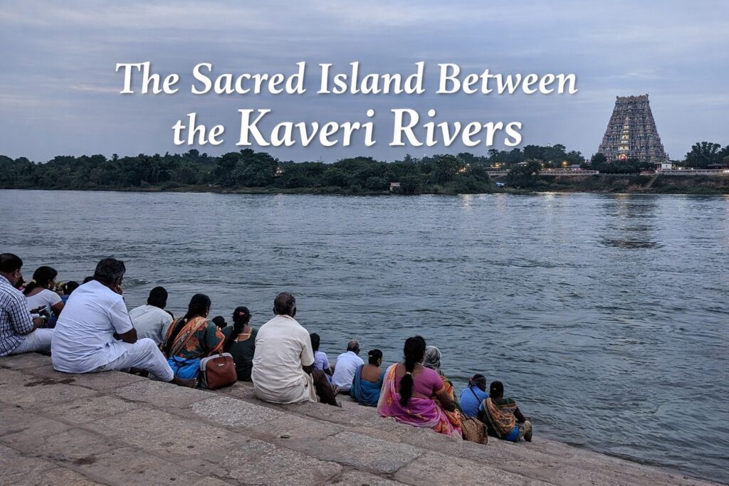 Devotees sitting at Kaveri river steps near Srirangam temple with gopuram visible in background